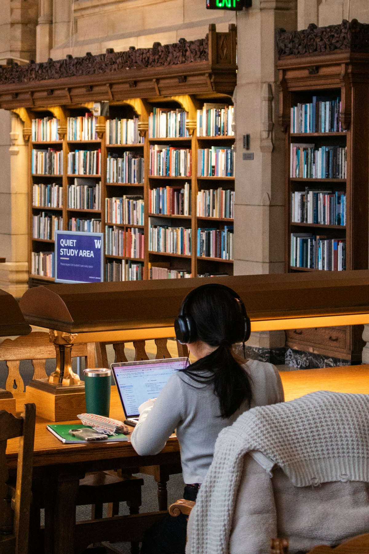 Étudiante en visio avec un casque dans une bibliothèque universitaire